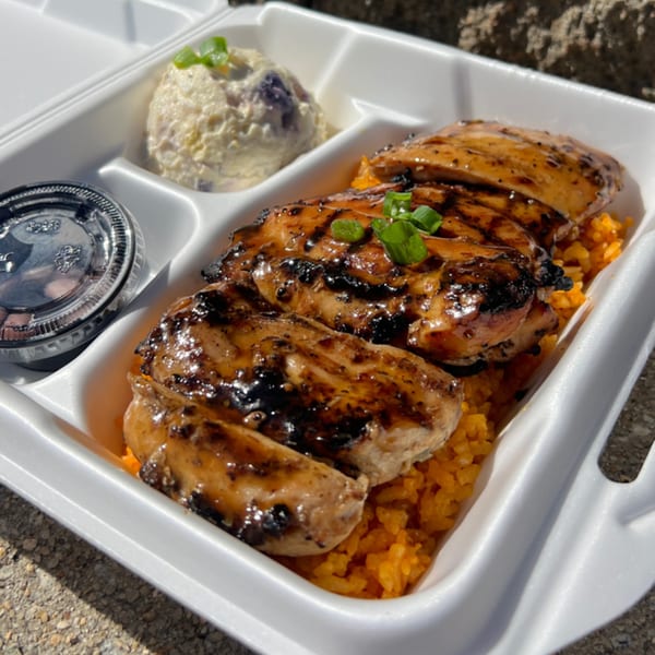 Legends Pacific Island Grill's teriyaki chicken, orange rice, and macaroni salad in a takeout container.