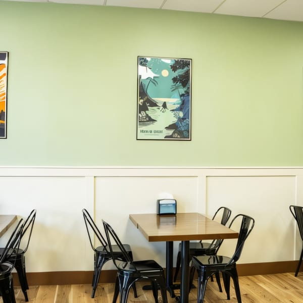 Legends Pacific Island Grill dining area with light green walls, white wainscoting, and black tables and chairs.