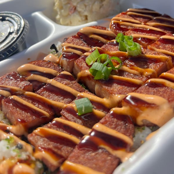 Legends Pacific Island Grill's Spam Musubi with sauce and green onions in a takeout container.