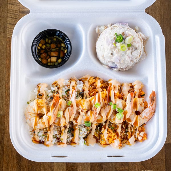 Hawaiian shrimp plate with rice, macaroni salad, and dipping sauce in a white takeout container.